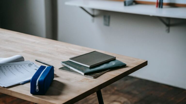 School bench with many copybooks and pencil case placed in light classroom against whiteboard
