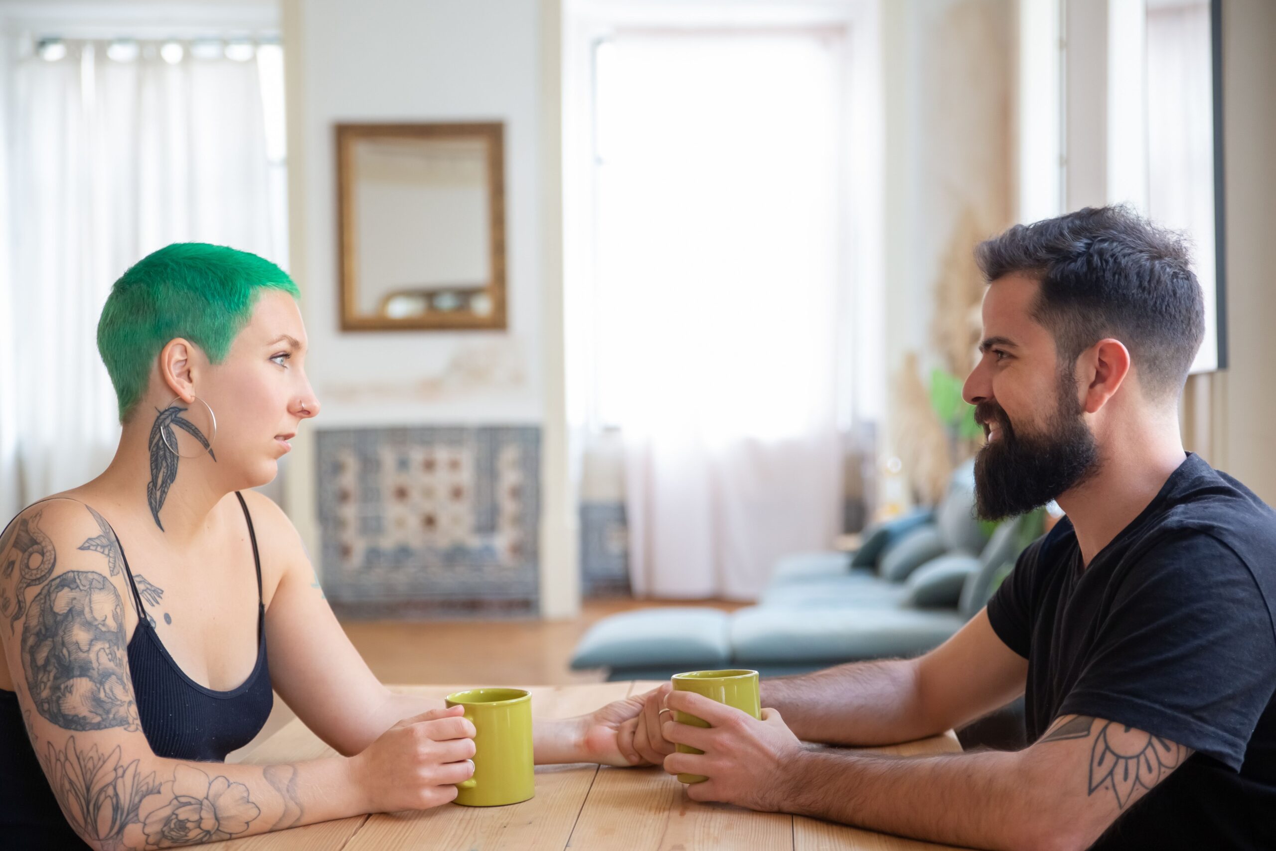 A couple sharing a warm conversation over coffee at home.